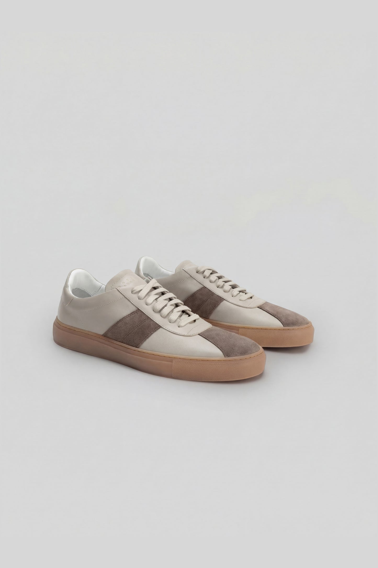 White and gray striped sneakers with tan rubber sole and lace-up closure, shown as a pair.
