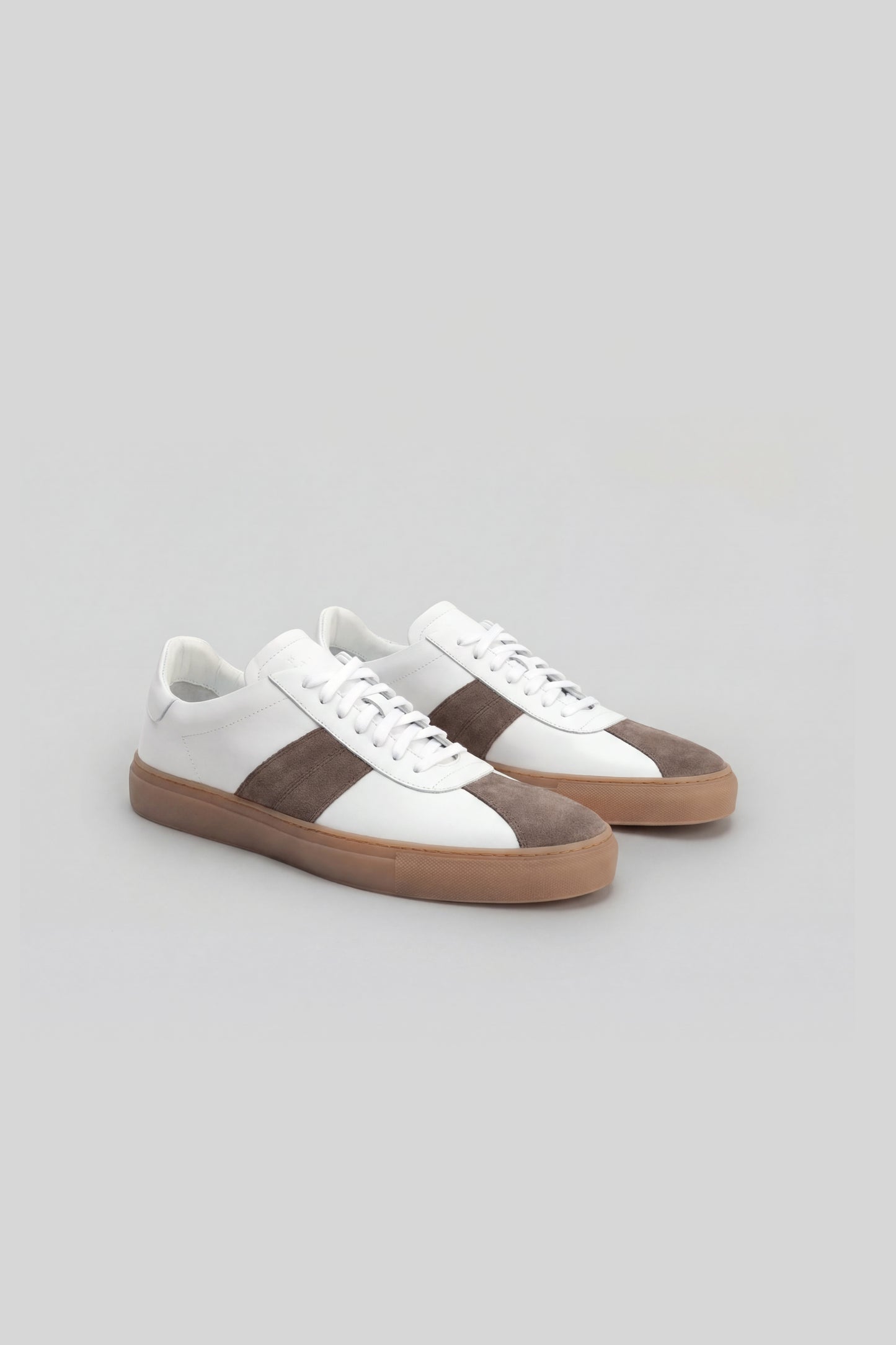 White and taupe striped sneaker with tan gum sole and white laces, shown from a three-quarter view.