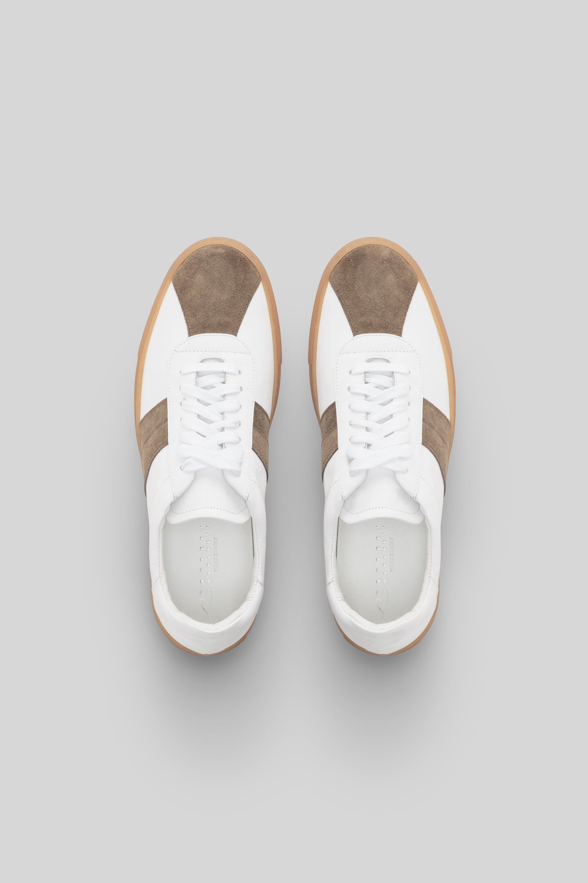 White sneakers with tan and olive suede stripe panels, white laces, and gum sole, shown from above.