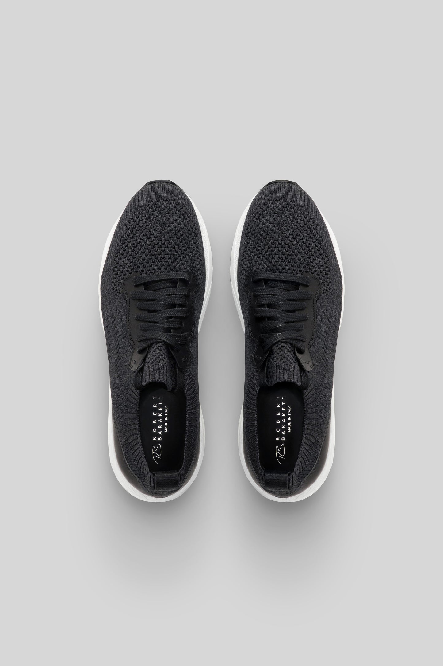 Pair of dark gray knit sneakers with black laces and white soles, shown from above.