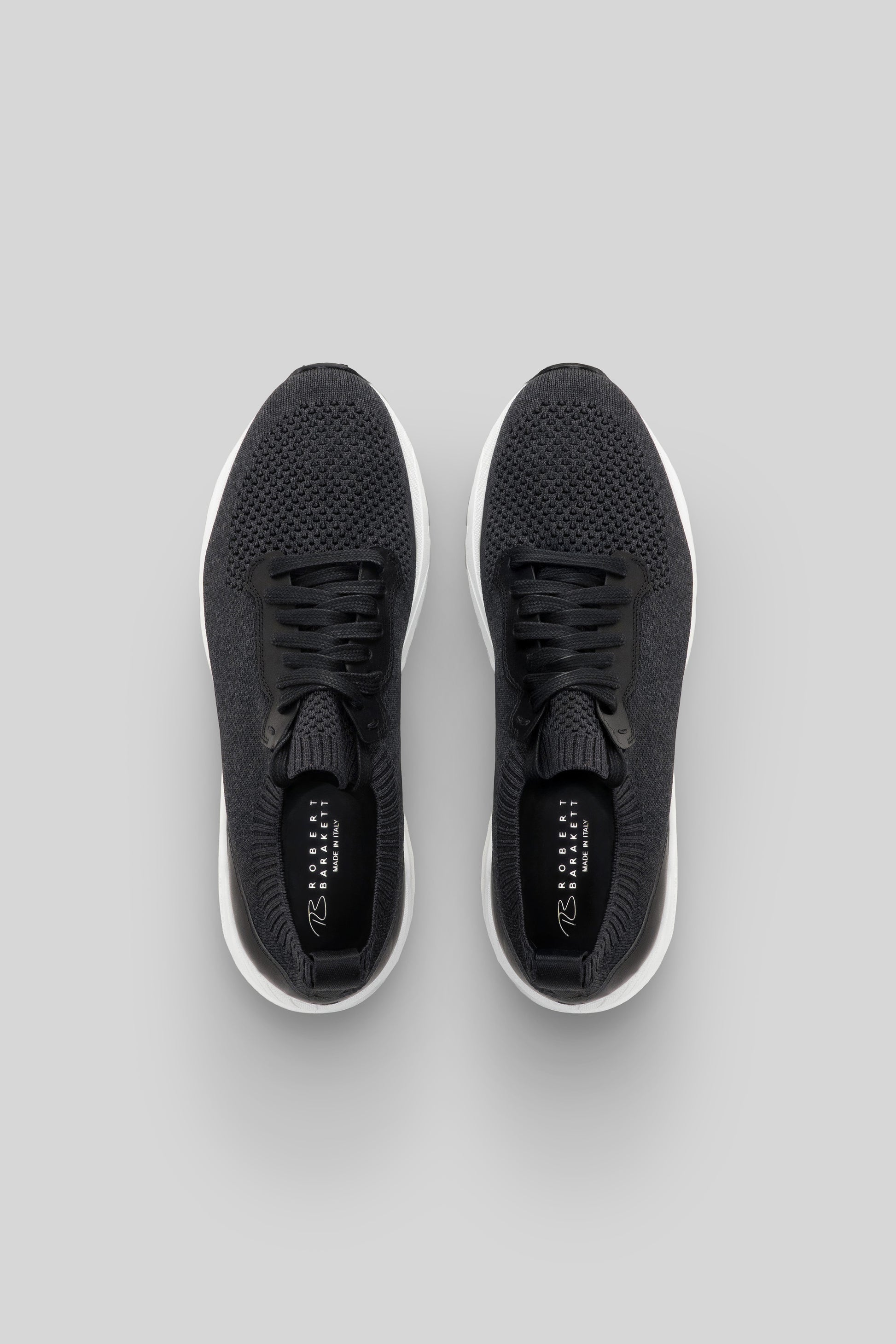 Pair of dark gray knit sneakers with black laces and white soles, shown from above.