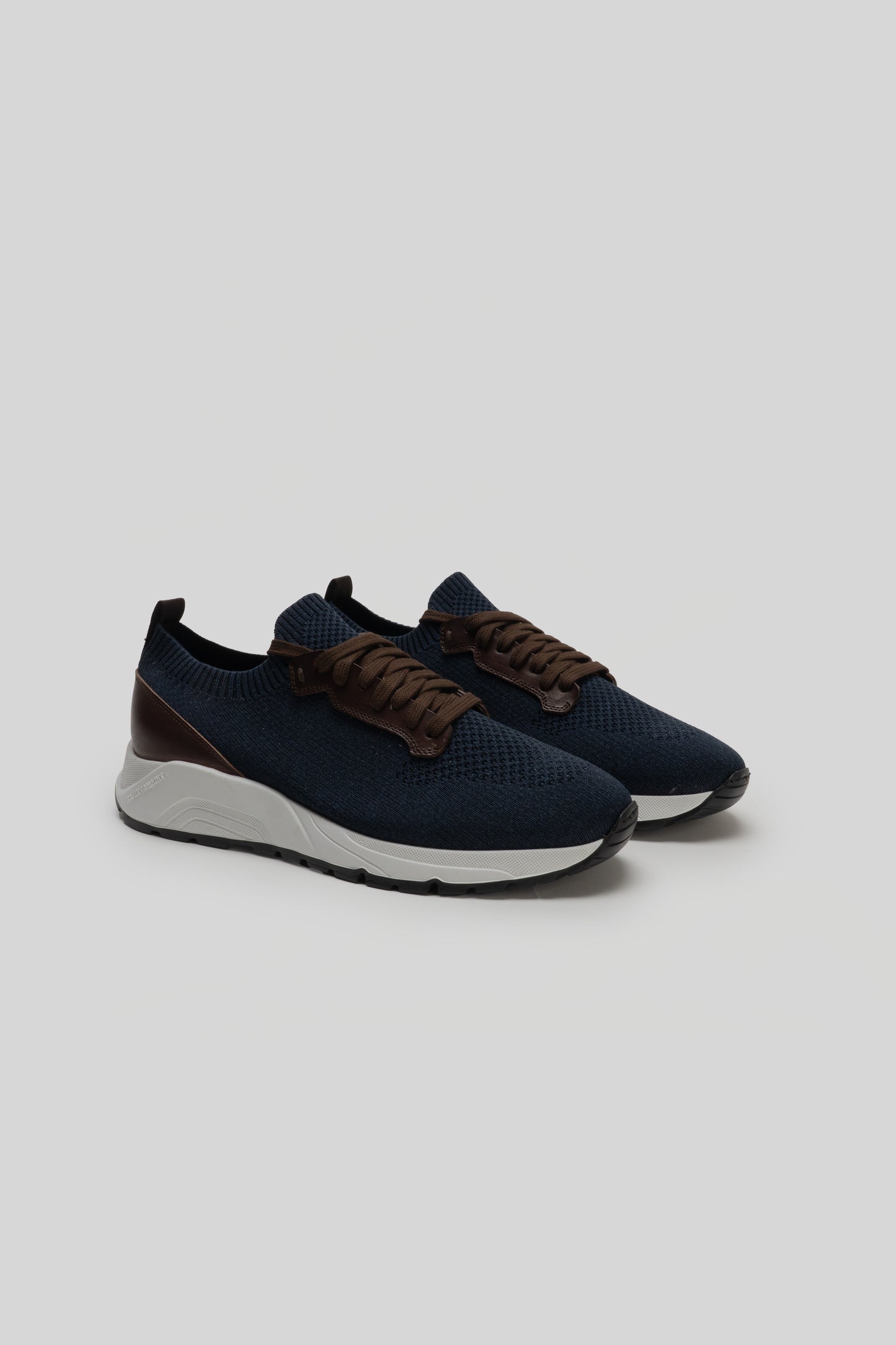 Navy knit sneakers with brown leather laces, white midsole, and black heel counter.