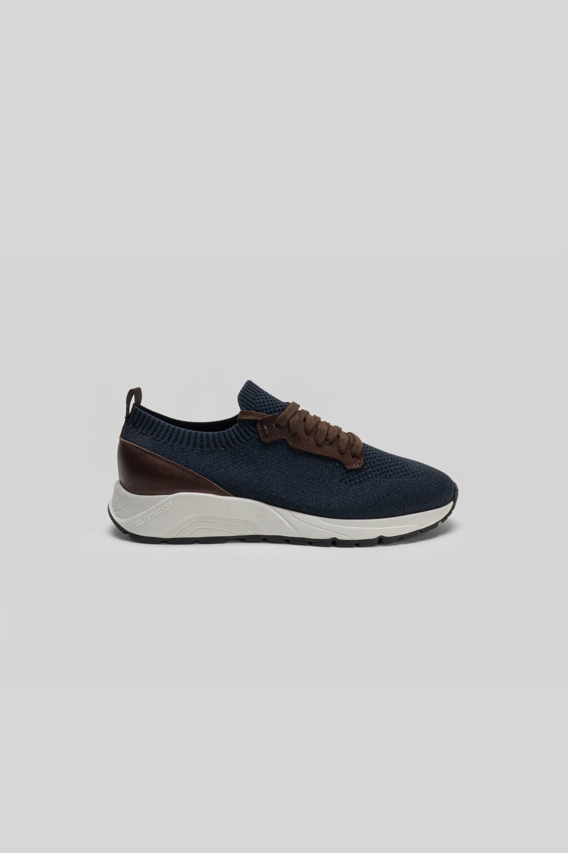 Navy knit sneaker with brown leather trim, white midsole, and black heel detail shown in profile view.