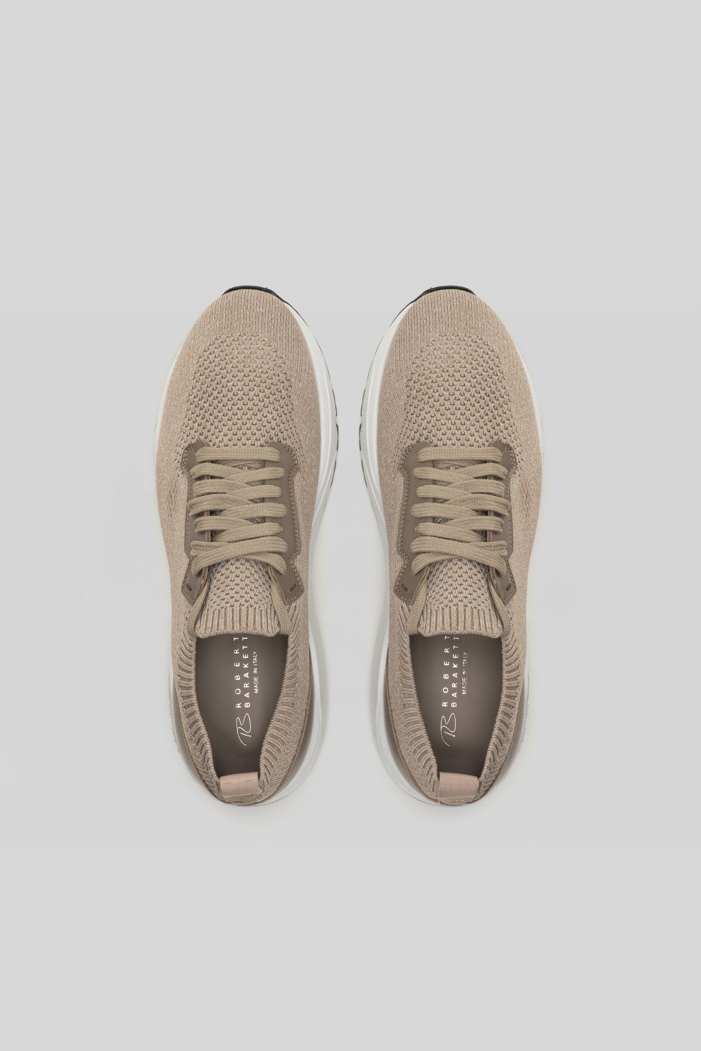 Pair of beige knit sneakers with white soles and tan laces, shown from above.
