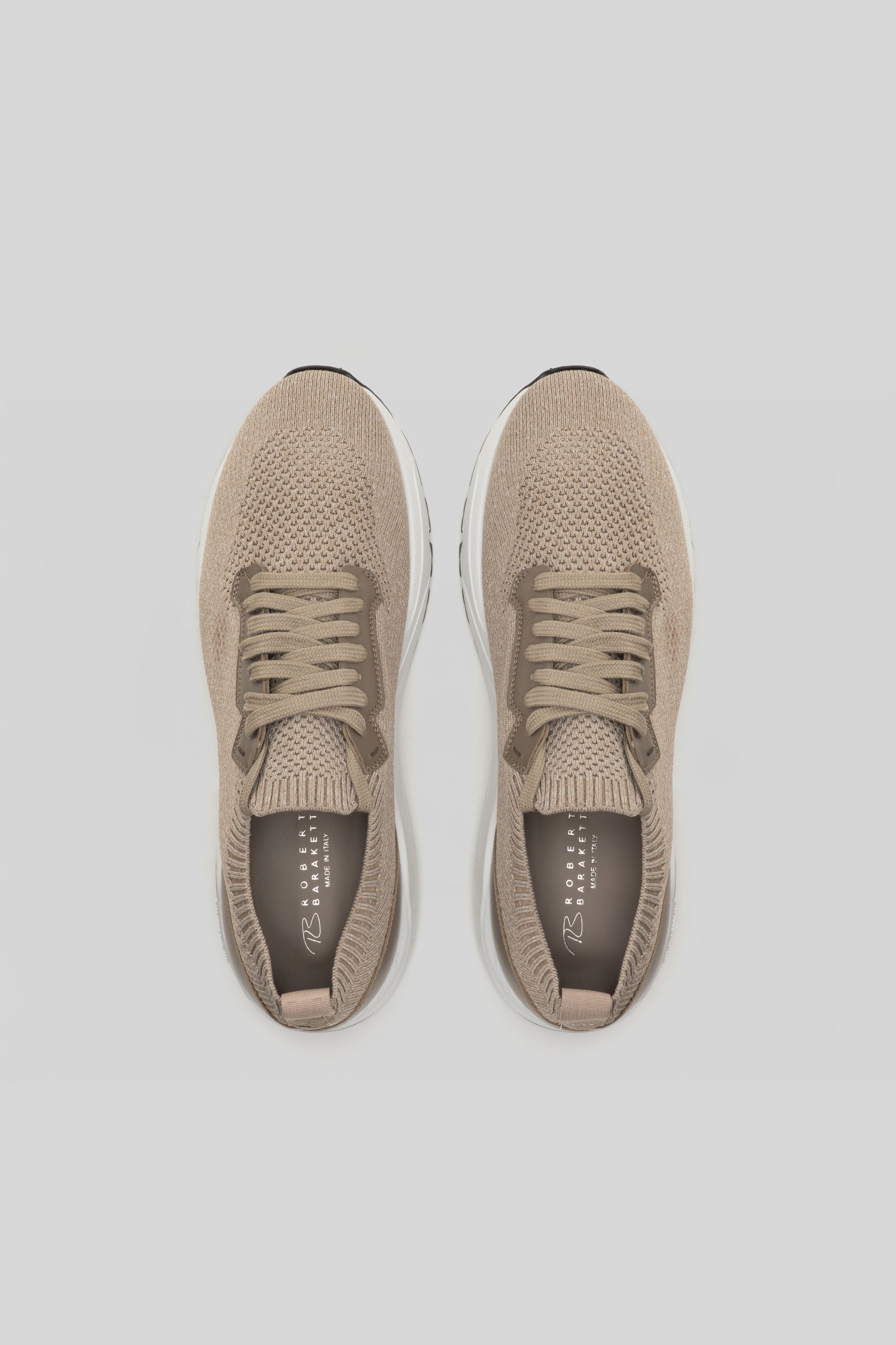 Pair of beige knit sneakers with white soles and tan laces, shown from above.