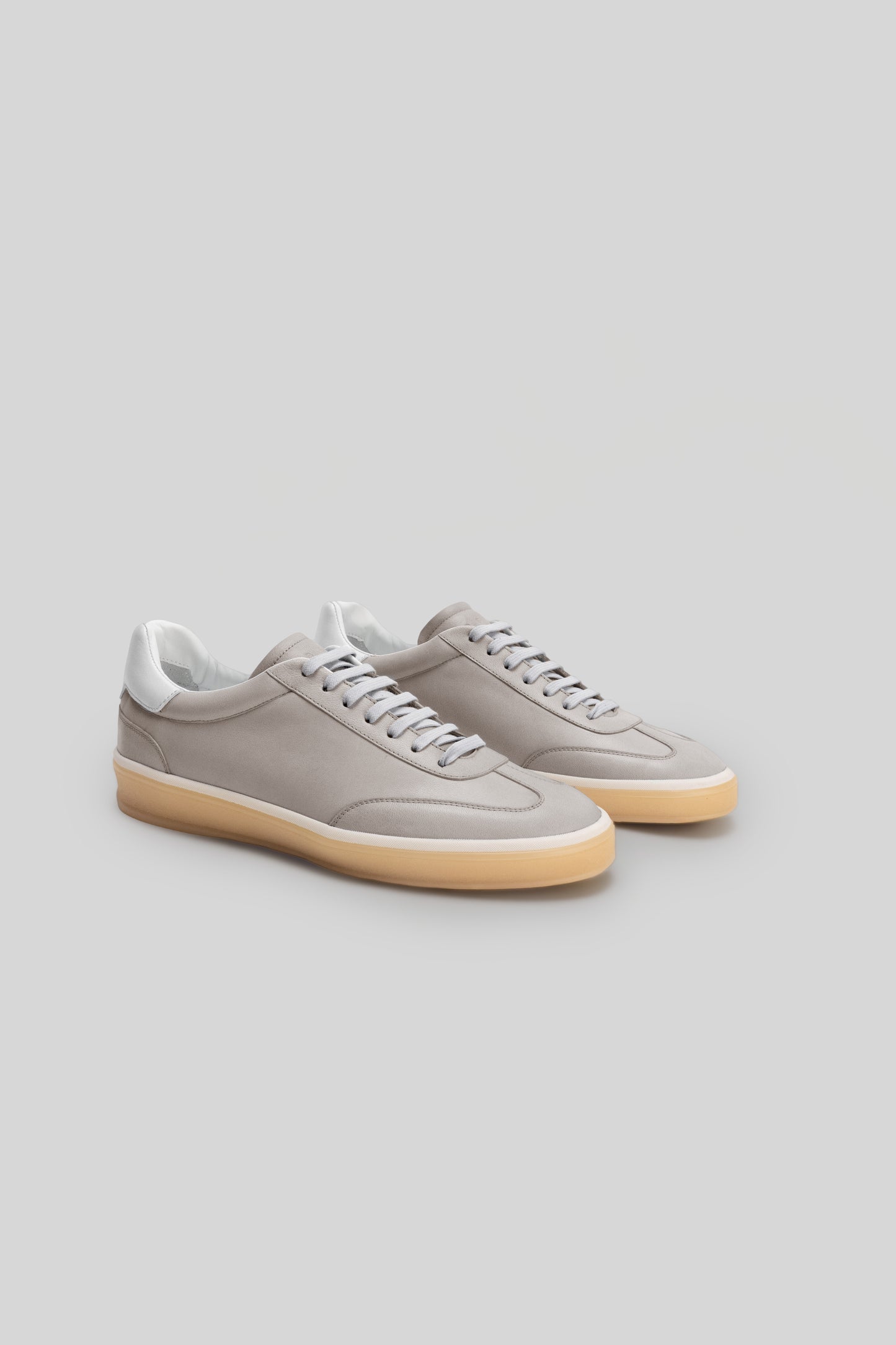 Pair of beige and white sneakers with cream-colored rubber sole and gray laces.