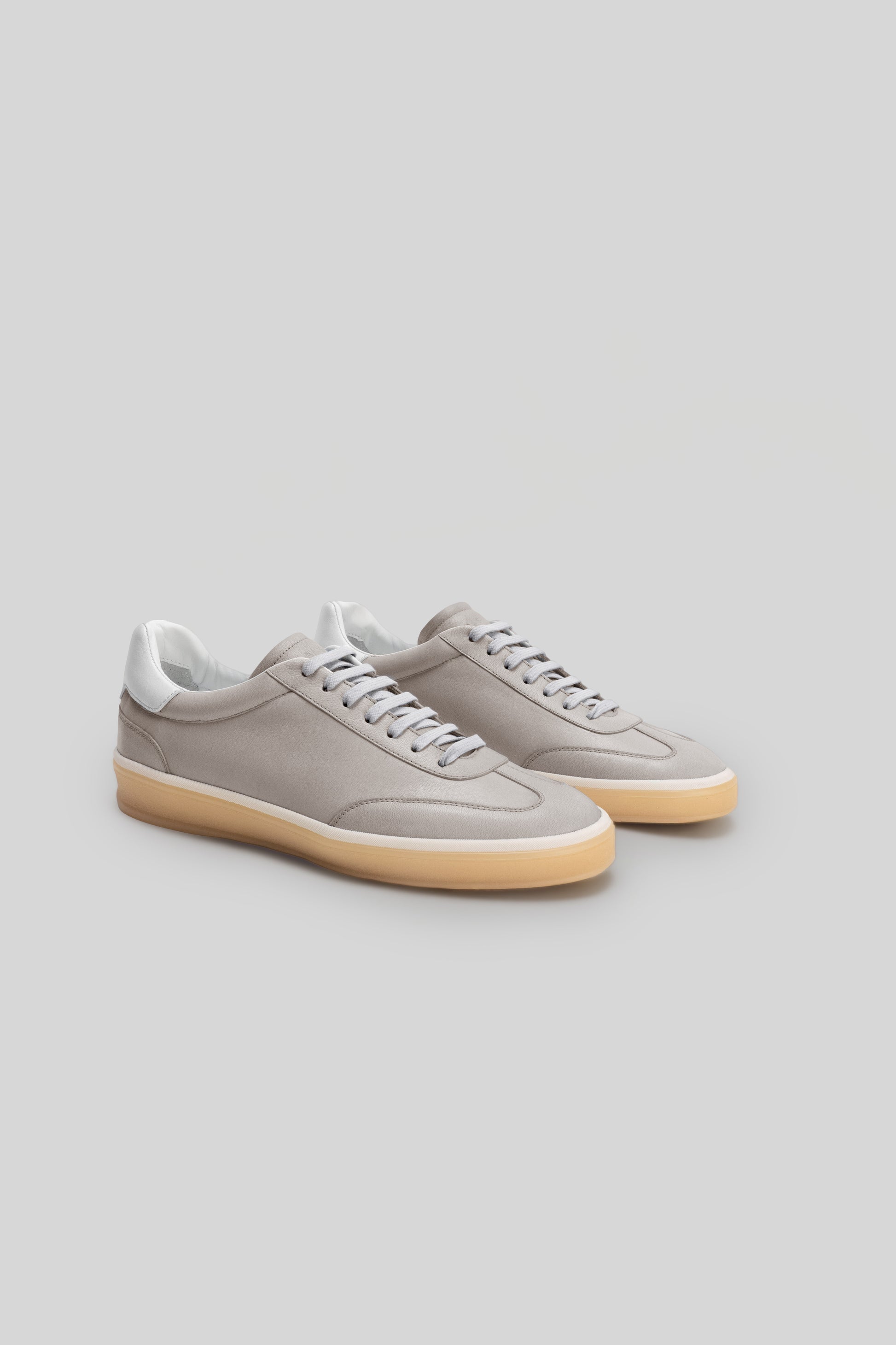 Pair of beige and white sneakers with cream-colored rubber sole and gray laces.