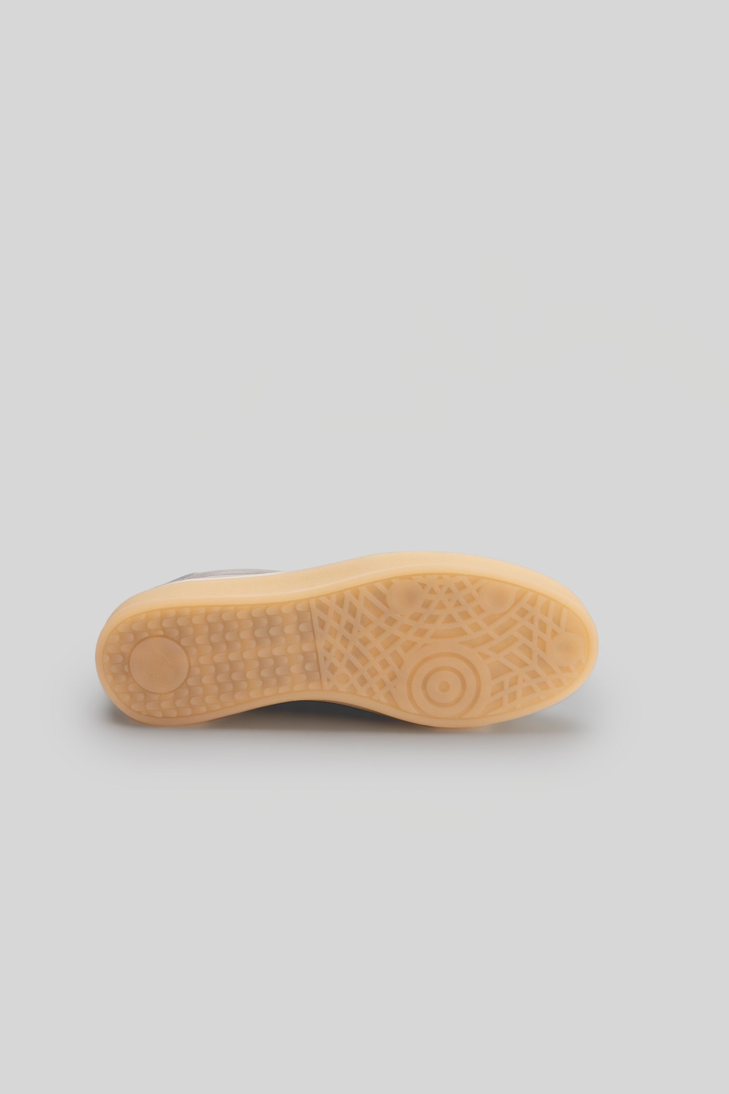 Tan and white sneaker sole with textured tread pattern and circular grip details.