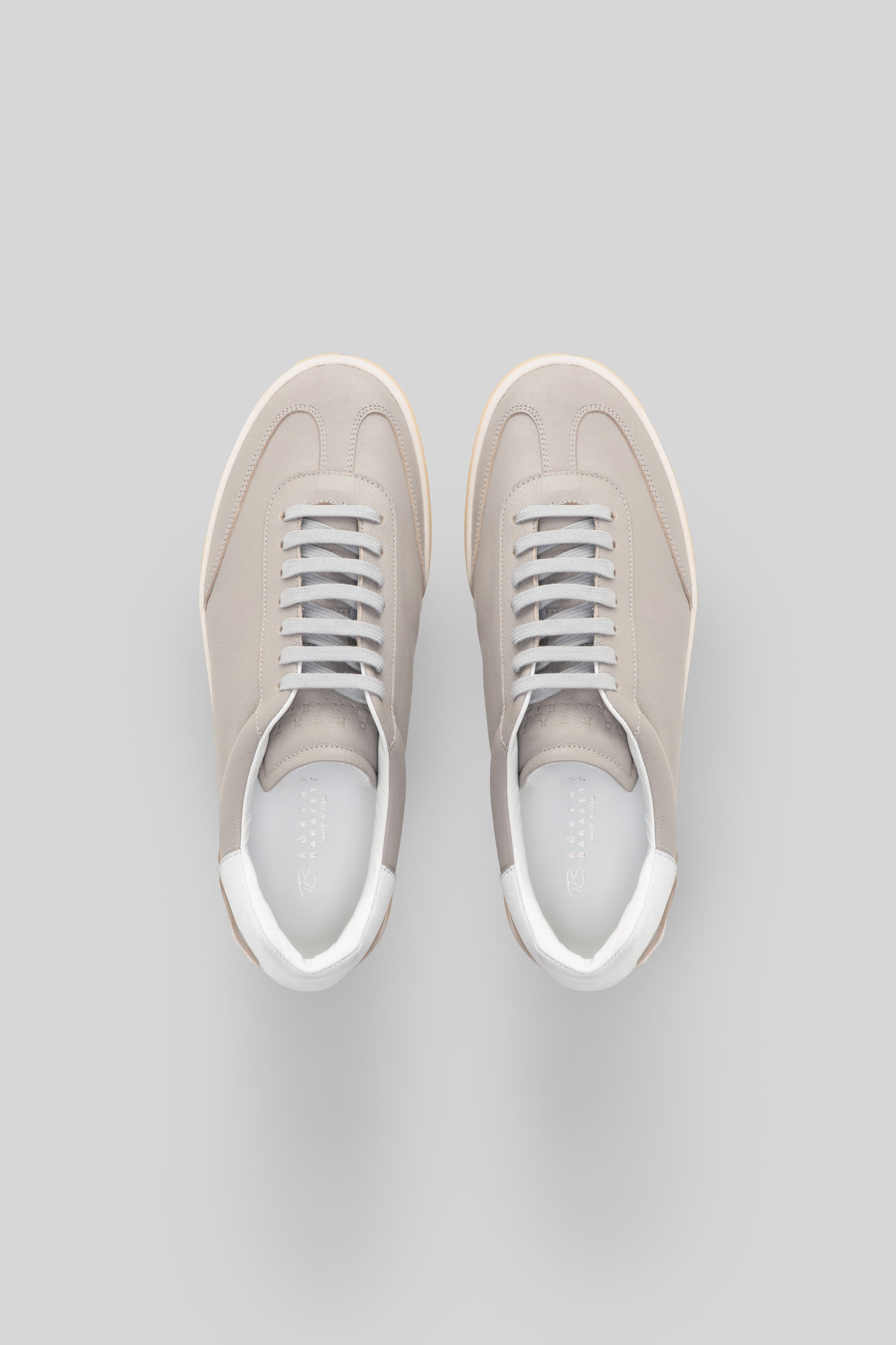 Pair of beige canvas sneakers with white laces and white rubber soles, shown from above.