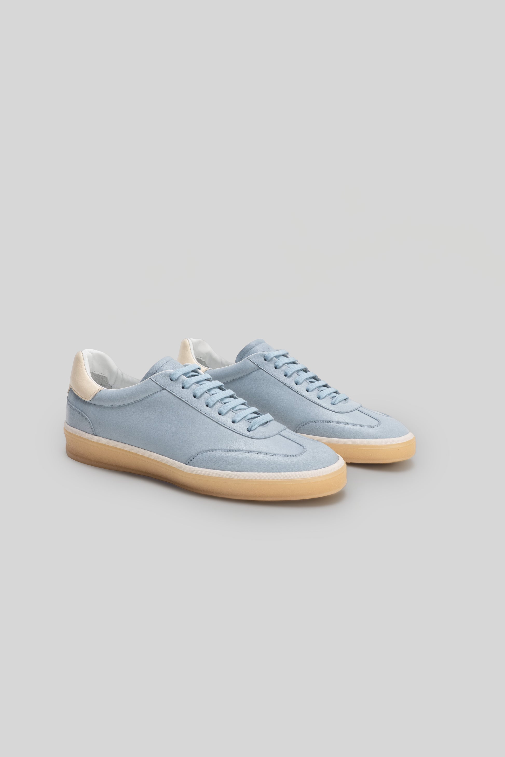 Pair of light blue lace-up sneakers with cream-colored heel collar and gum sole.