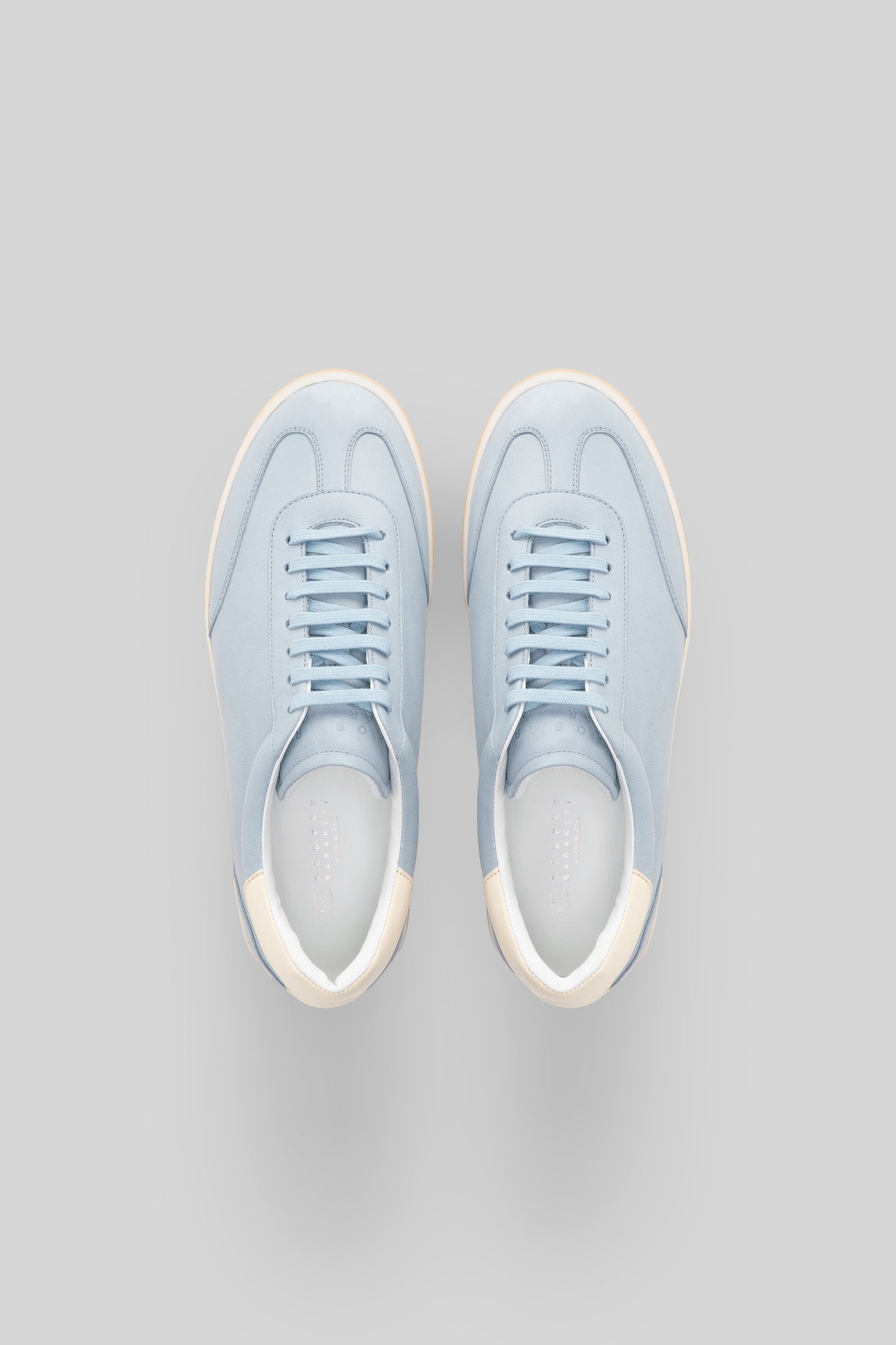 Pair of light blue sneakers with cream-colored heel and toe caps, viewed from above.