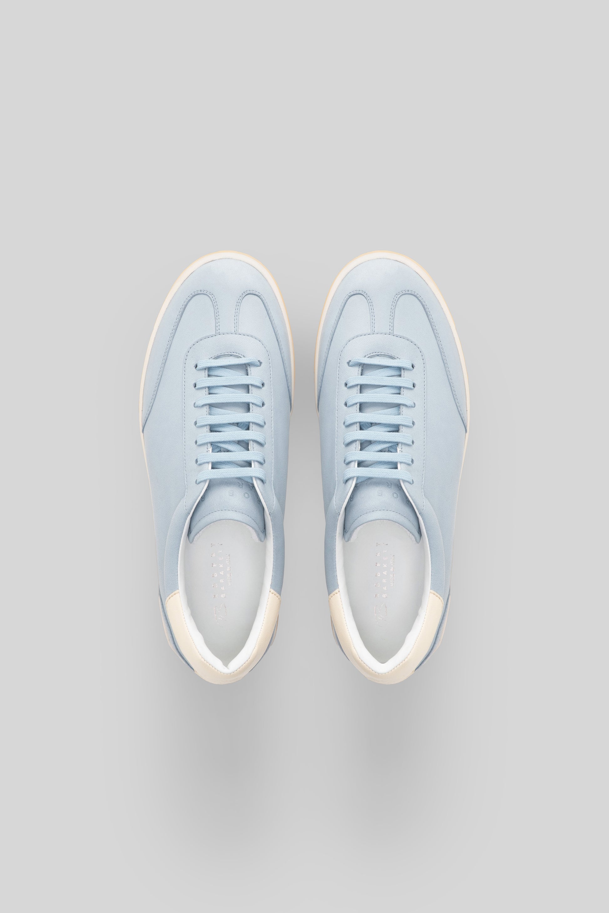 Pair of light blue sneakers with cream-colored heel and toe caps, viewed from above.