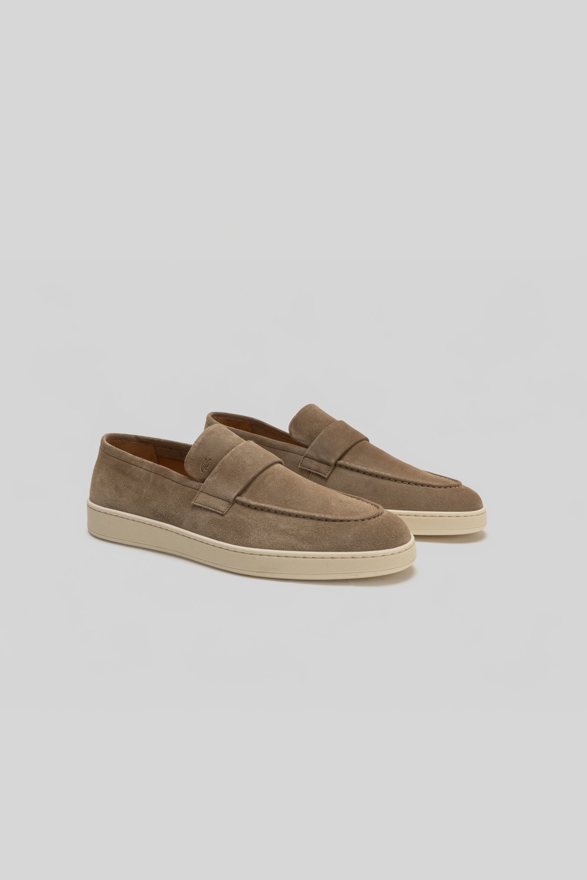 Pair of tan suede loafers with cream-colored rubber sole and stitched penny slot detail on upper.