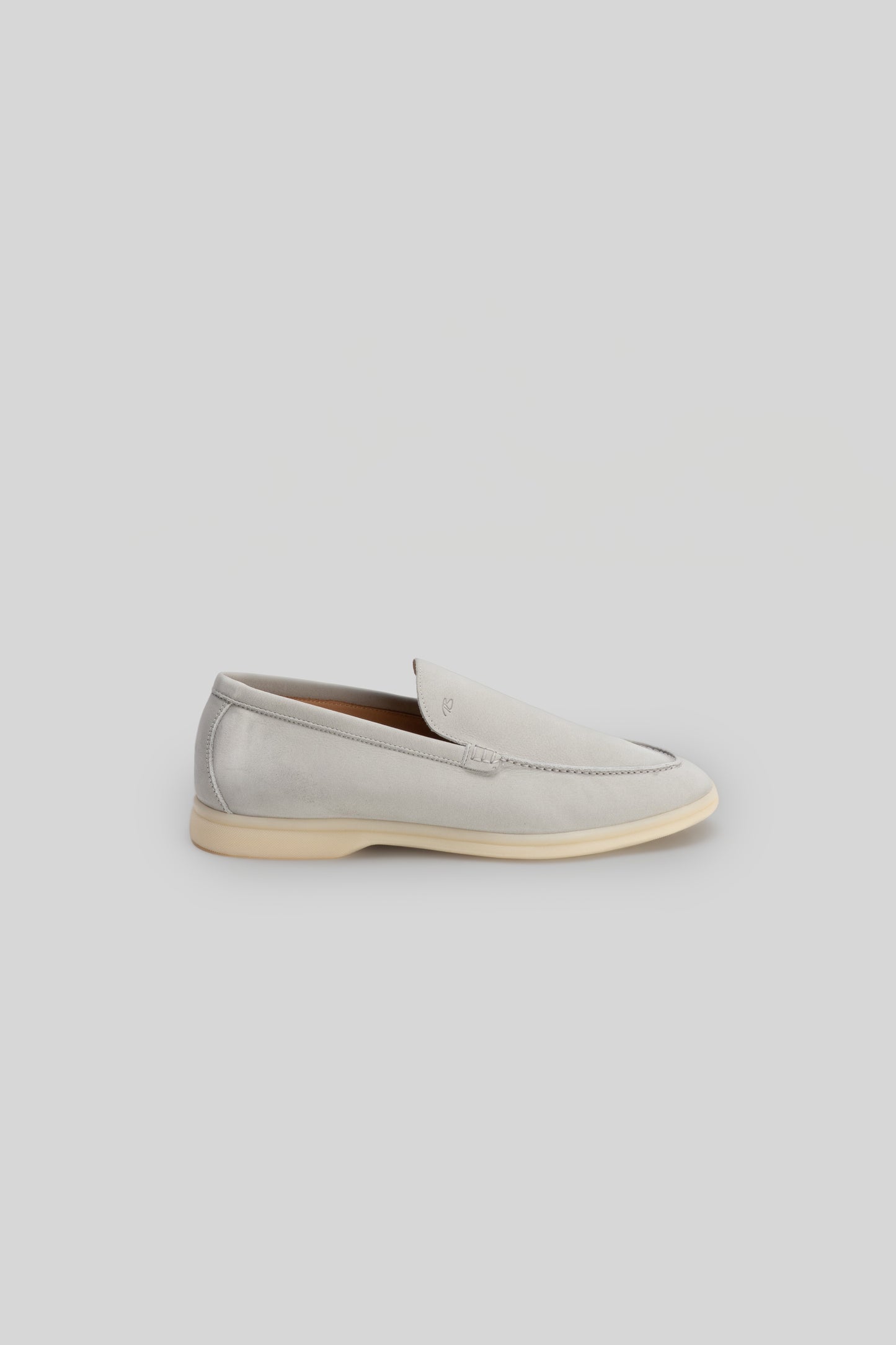 Beige suede loafer with cream rubber sole and stitched toe detail, shown in side profile.
