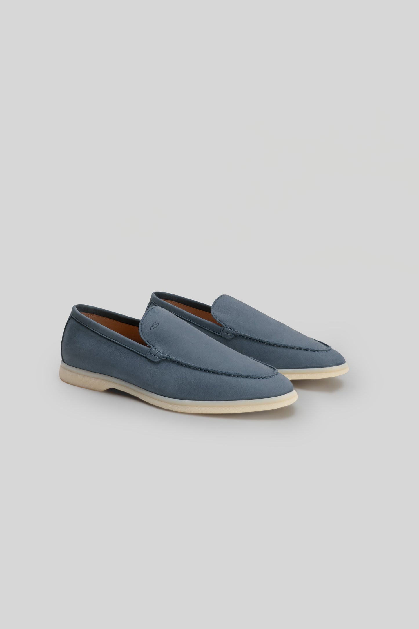 Blue leather loafers with cream-colored rubber sole and stitched detailing on the vamp.