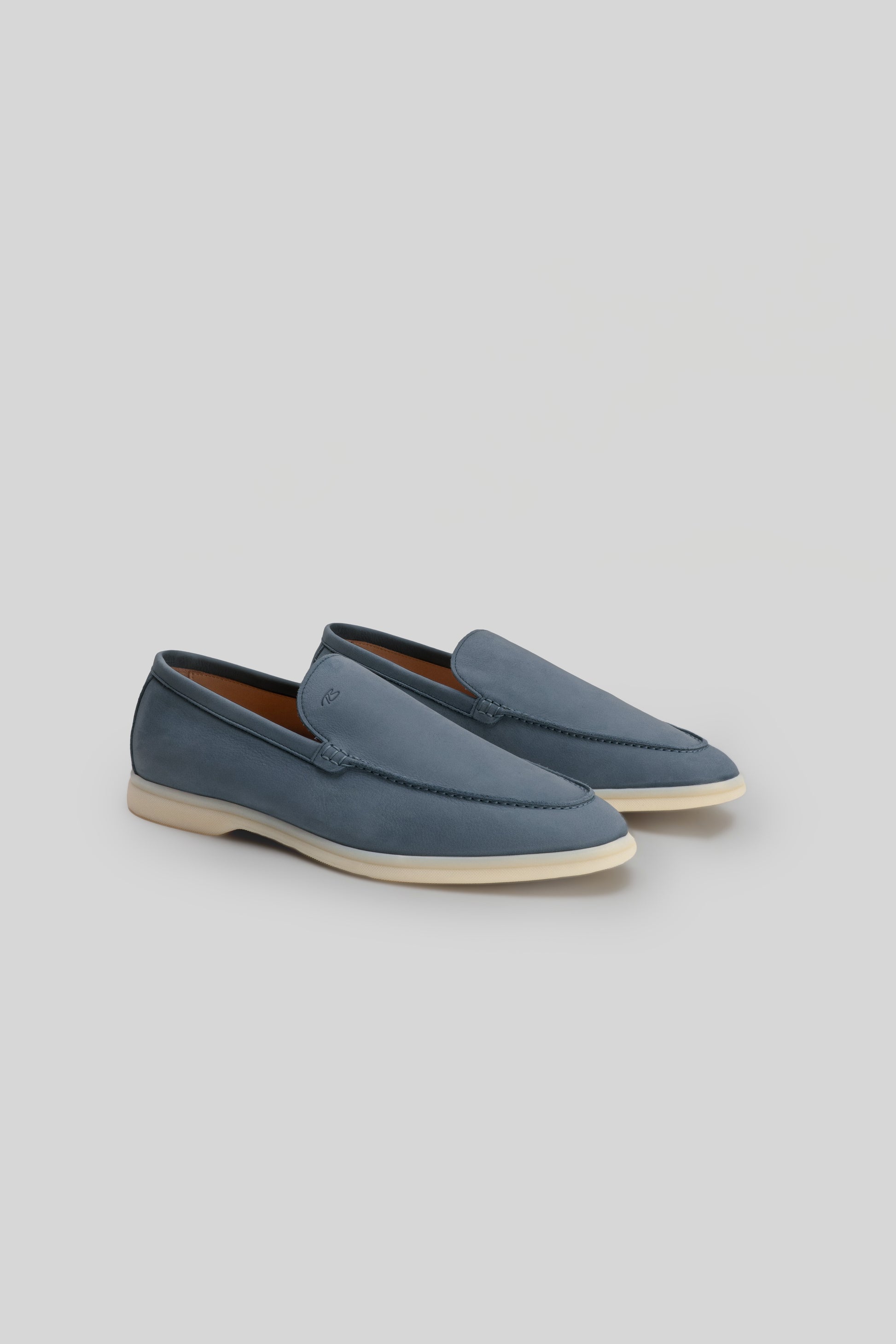 Blue leather loafers with cream-colored rubber sole and stitched detailing on the vamp.