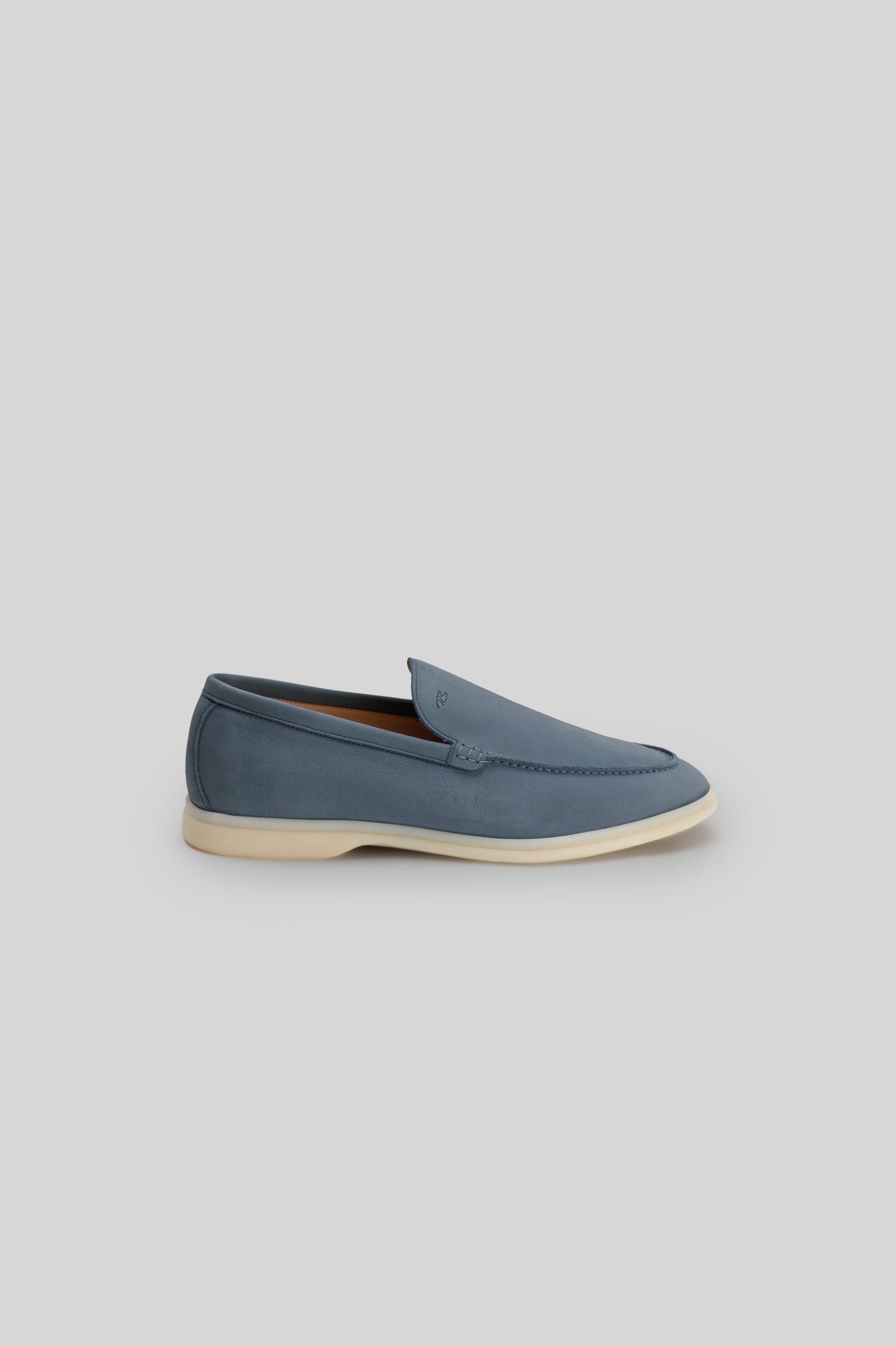 Blue suede loafer with cream sole, displayed in profile view against a neutral background.