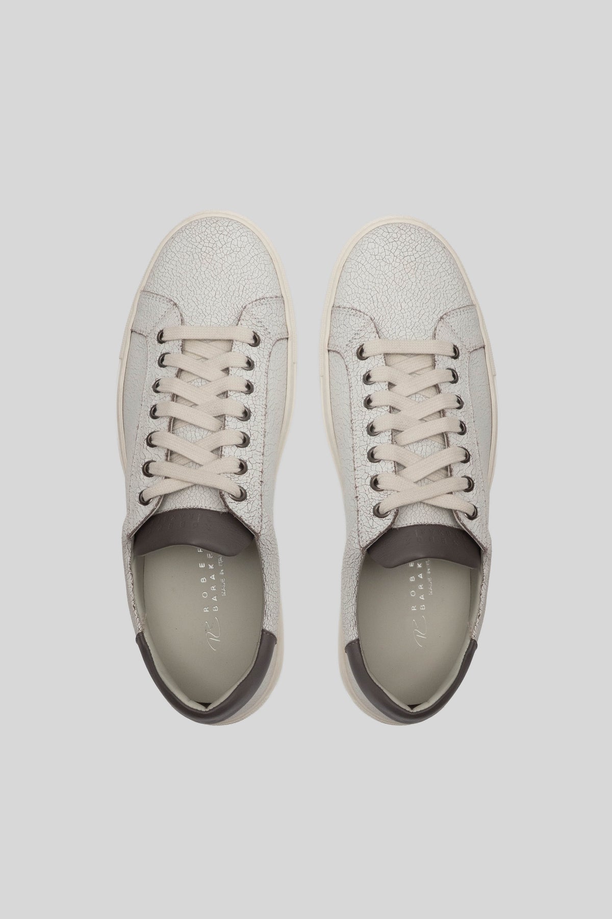 White leather sneakers with lace-up closure and dark heel counter, shown from above.