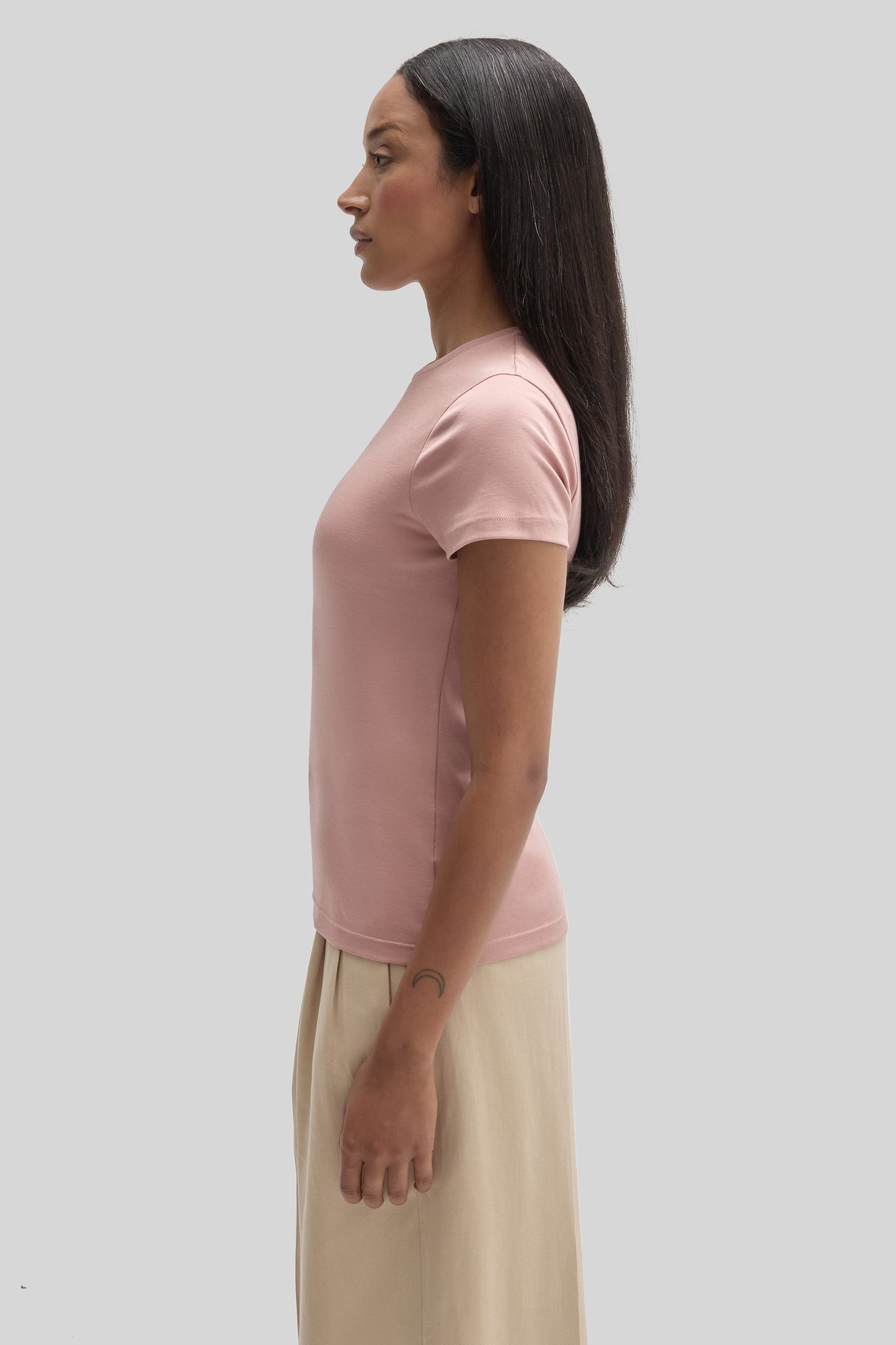 Woman wearing a light pink short-sleeve t-shirt, shown in side profile view.