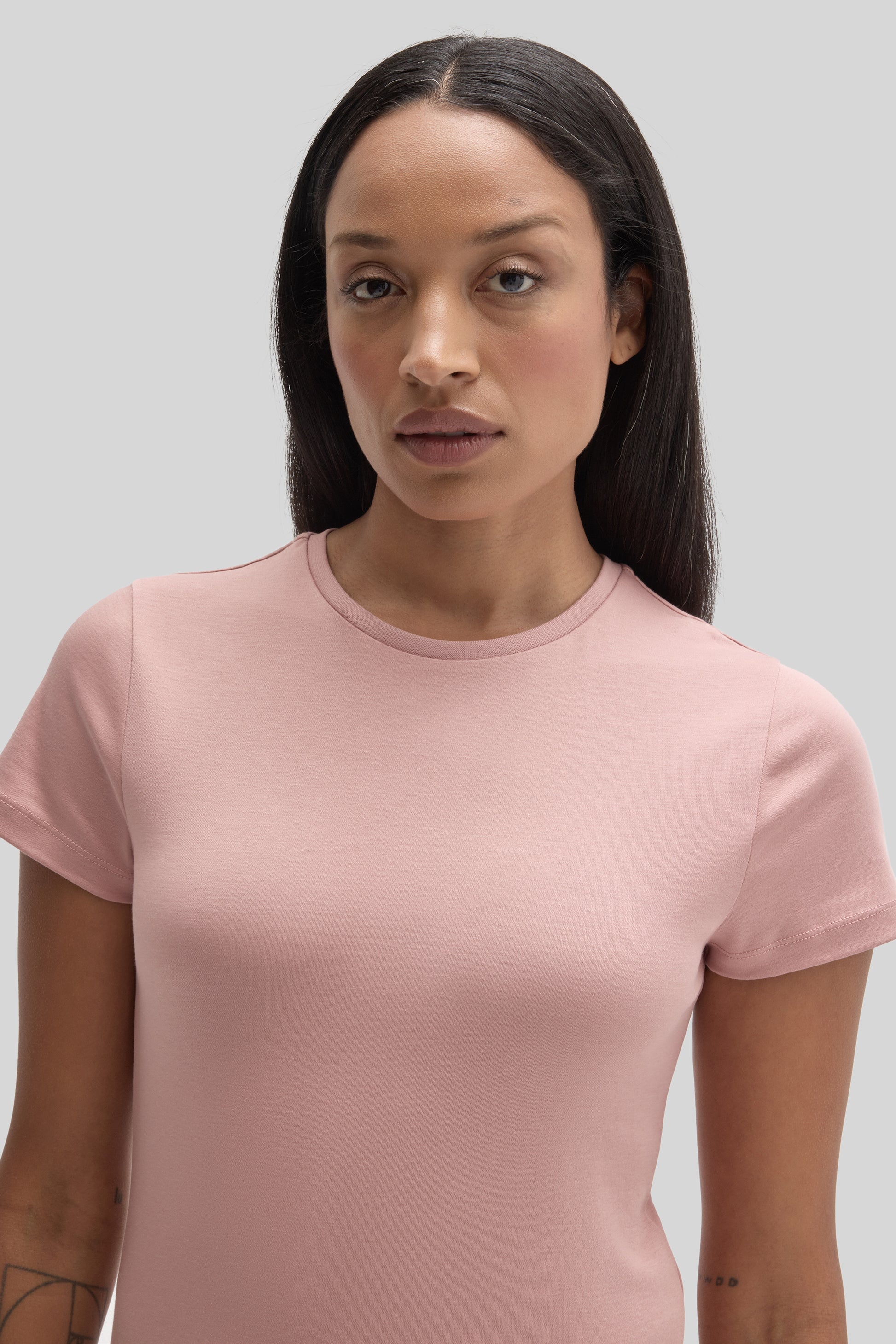 Woman wearing a pink short-sleeve crew neck tee with a fitted silhouette.