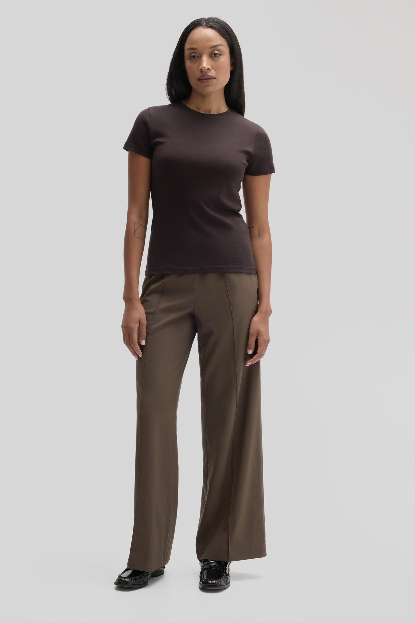 Woman wearing dark brown short-sleeve crew neck tee with olive wide-leg pants and black loafers.