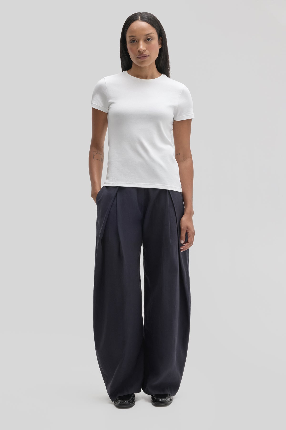 Woman wearing white short-sleeve crewneck tee with dark navy wide-leg trousers.