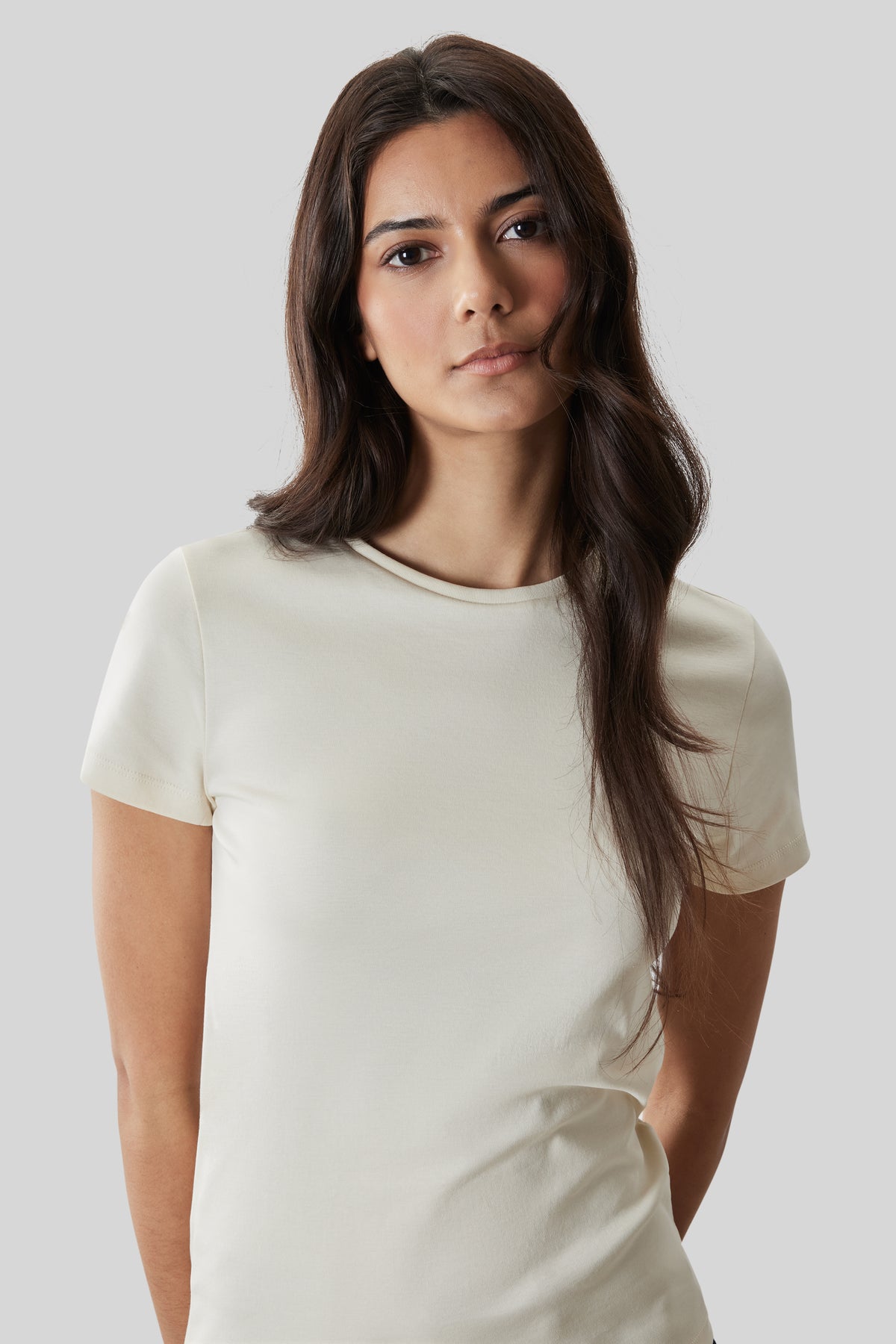 Woman wearing a cream-colored short-sleeve crewneck tee with a relaxed fit.